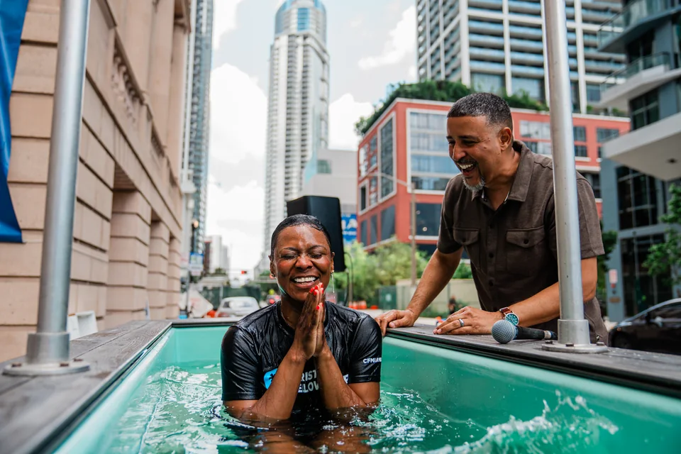 A person celebrating a baptism with city buildings behind them.