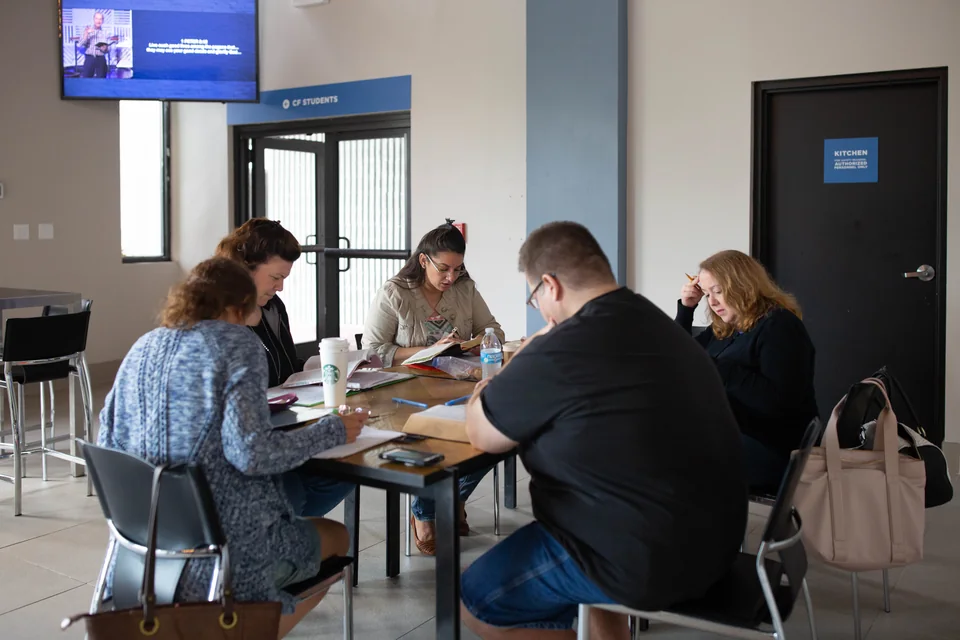 People gathered around a table with books and notes.